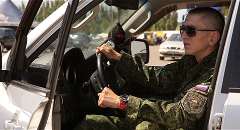 Still image of a man in military clothing sitting in car form the film Olegs Choice.