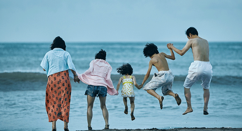 a family jumps in the air on the beach from the film Shoplifters.