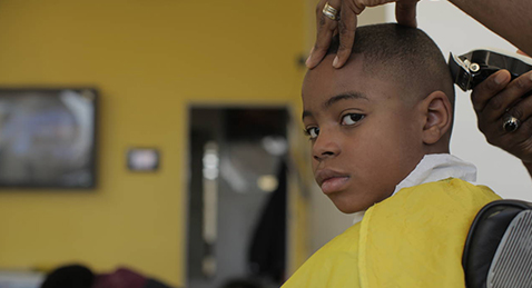 Still image of a boy getting his hair cut from the film The Fade.