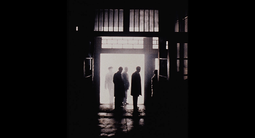 a crowd stands in the shadows from the film After Life