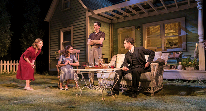 a family sits outside having drinks from the National theatre live production of All My Sons