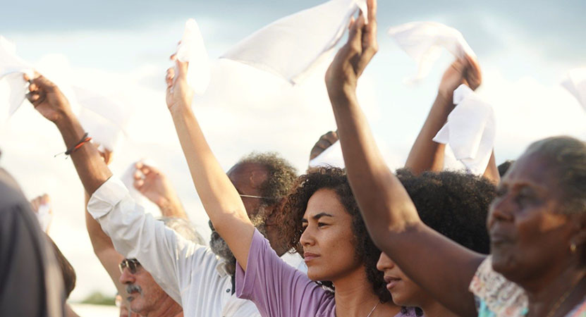 a group of people raise there arms in the air from the film Bacurau.