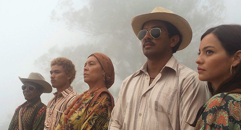 a group of people stand outside from the film Pájaros de verano (Birds of Passage).