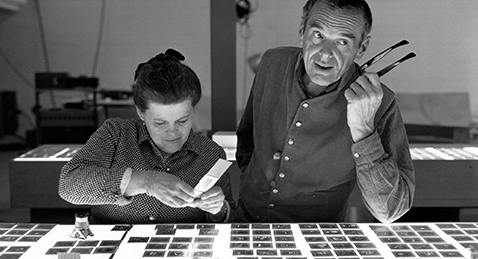 Still image of Charles and Ray Eames looking at photo negatives from the film Eames: The Architect and the Painter.