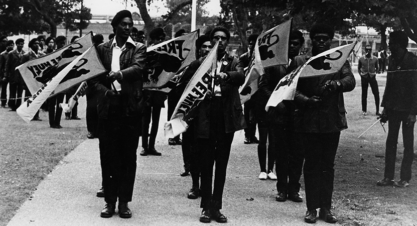 a group marches with flags from the film in the event We Tell: Environments of Race and Place