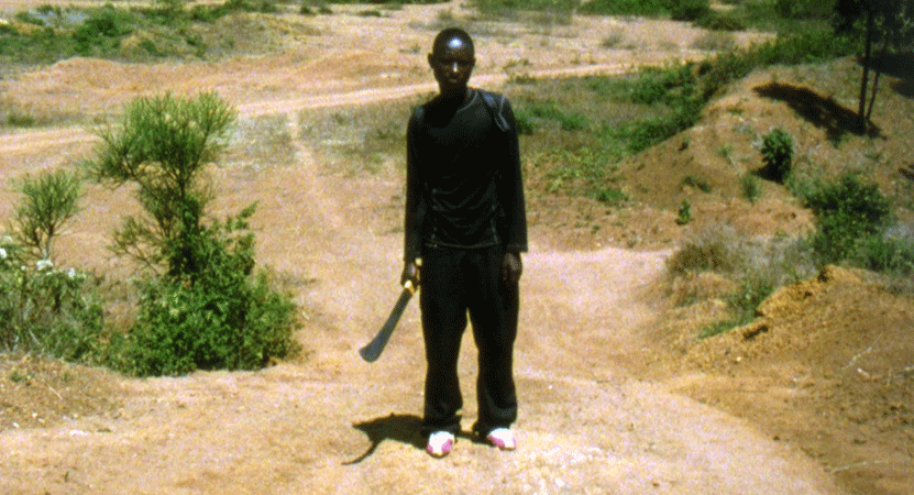 man stands with a machete from the film Munyurangabo.