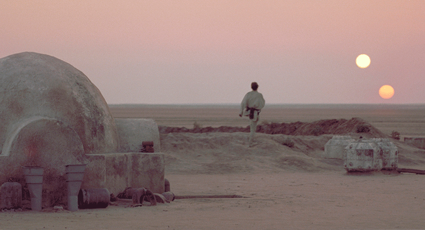 Luke Skywalker walks out of his house on Tatooine while the sun sets.