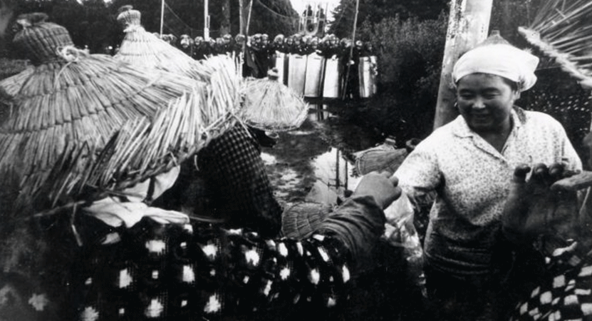 a person hands another person a bottle from the film Summer in Sanrizuka