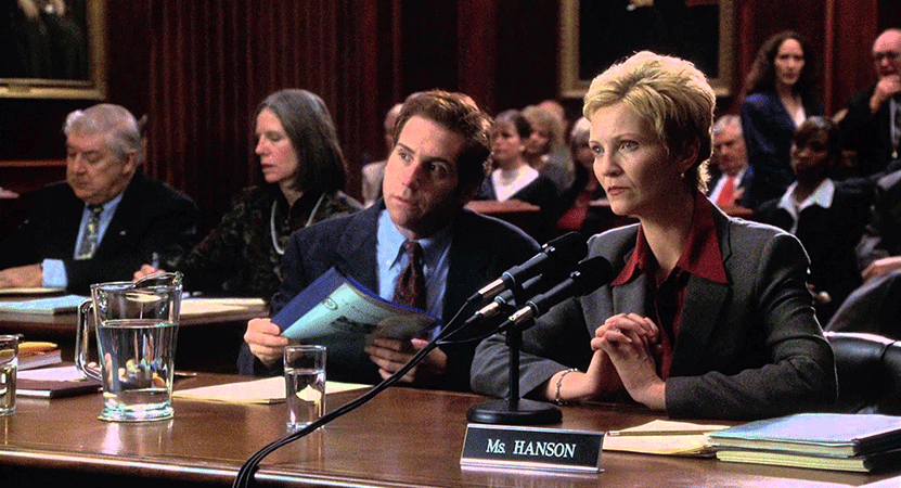 lawyers sit at a table in a court room from the film The Contender.