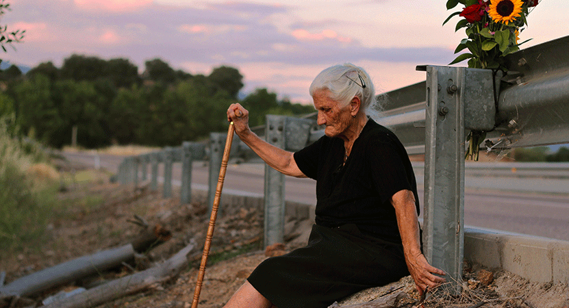 an elderly women sits by the road from the film The Silence of Others