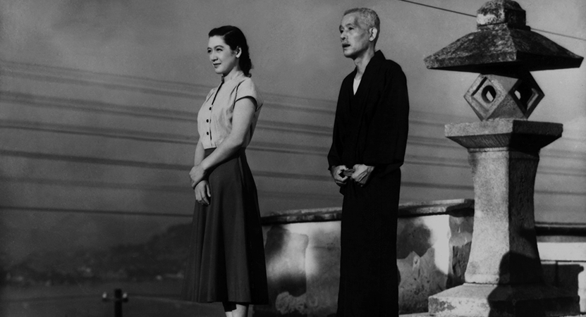 a man and women stand in front of a statue from the film Tokyo Story