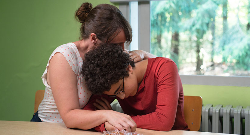 a women comforts a you person from the film Young Ahmed.